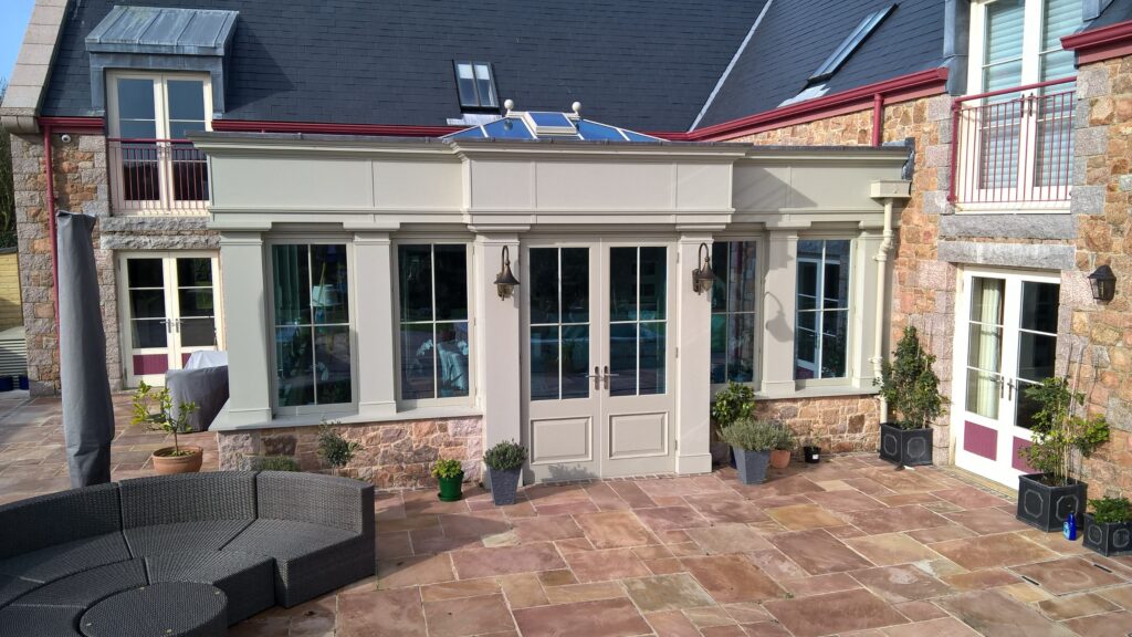 Glazing Exterior French Doors And Windows With Stone Wall And Patio Seating Trinity Joinery Jersey 2500