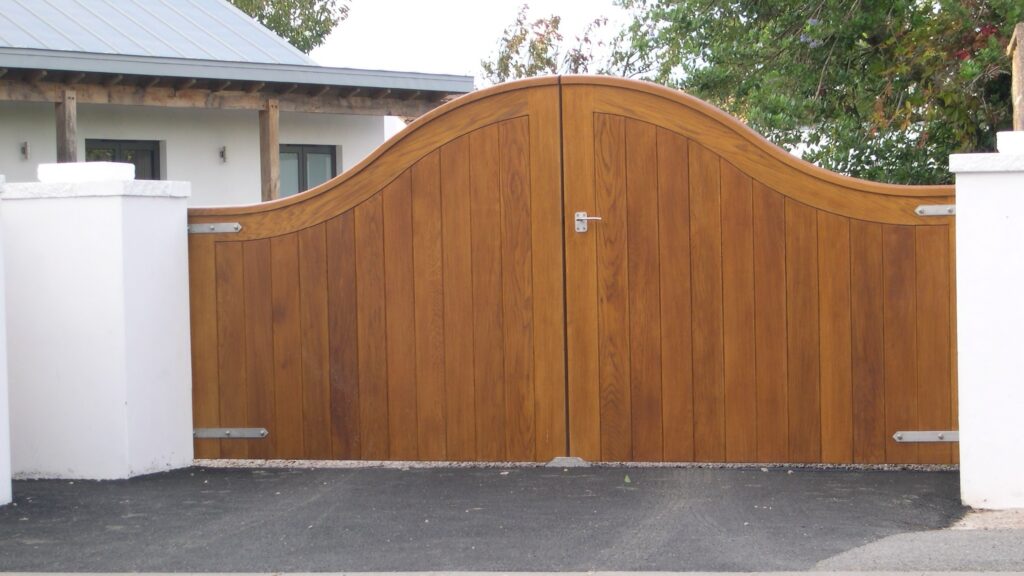 Iroko Wood Driveway Gates Wave Top Modern Design White Pillars Trinity Joinery Jersey 2500