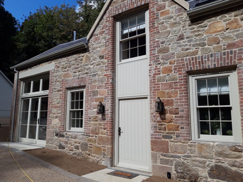 Timber Front Door With Vertical Panels And Sash Windows With Georgian Bars Painted Light Grey Trinity Joinery Jersey 2500