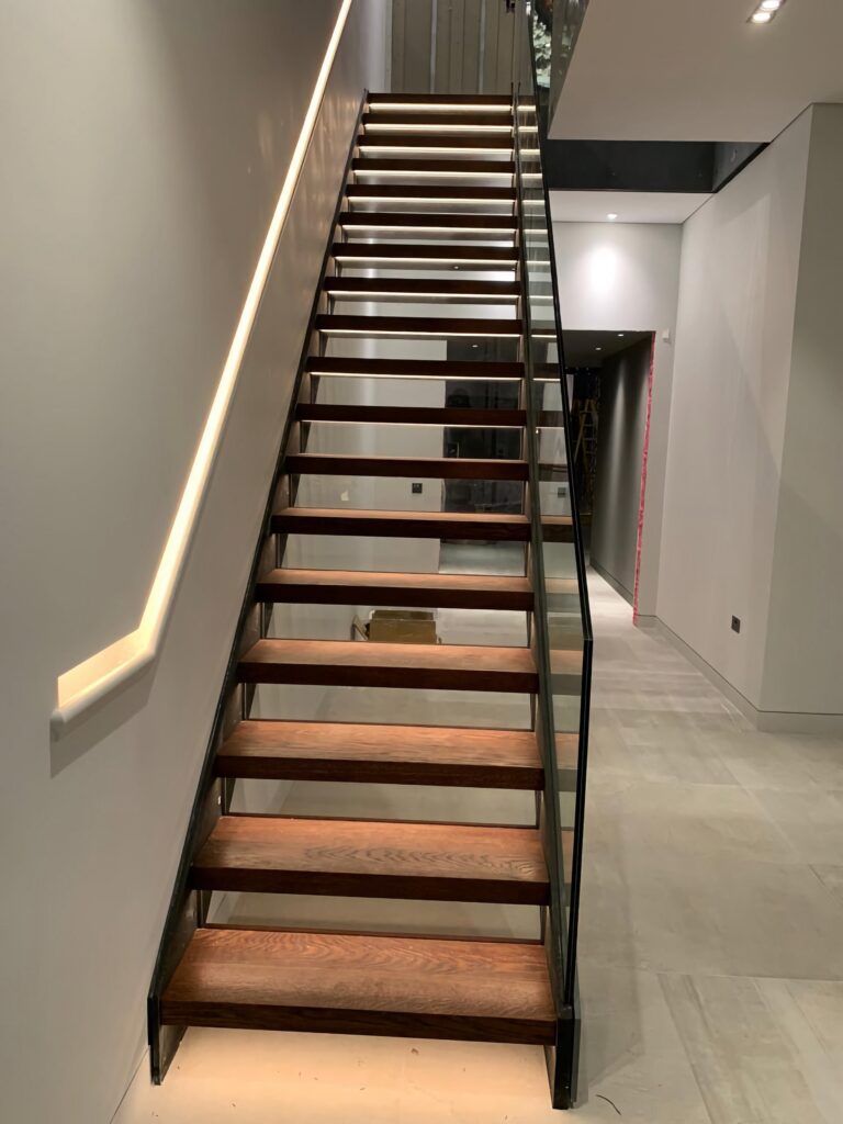 Timber Staircase With Glass Balustrade And Led Lighting Front View Staircases Balustrade Trinity Joinery Jersey 2500